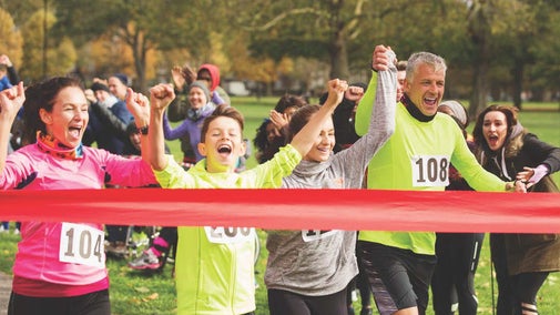 The image shows people in bright colours taking part in a race